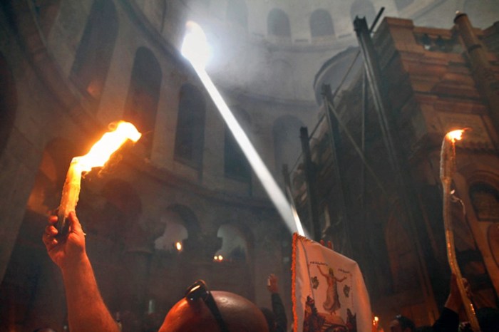 epa02699556 An Eastern Orthodox Christian with his burning candles during the miracle of the Holy Fire as a shaft of light enters the rotunda and he passes the Tomb of Christ (R) in the Church of the Holy Sepulchre in Jerusalem on 23 April 2011, the day before Easter. The fire comes forth from a hole in the Tomb of Christ and quickly spreads among the faithful in the church and then outside through Jerusalem and even to foreign countries. The miracle is recorded as happening each year since 1106 and is considered by believers to be the flame of the Resurrection power, as well as the fire of the Burning Bush of Mount Sinai.  EPA/JIM HOLLANDER